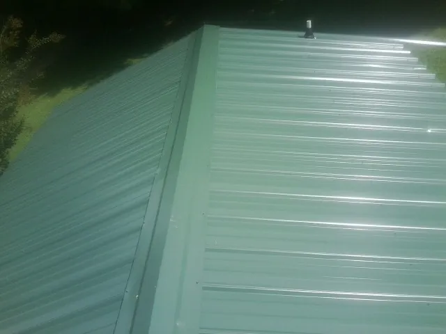 New green metal panels meeting at the ridge of a roof — Flat Roof Repair work by our crew in Priest River