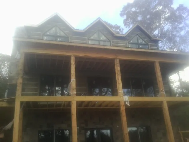Dormers and porch framing on a large log home under construction — Roof Coating work by our crew in Priest River