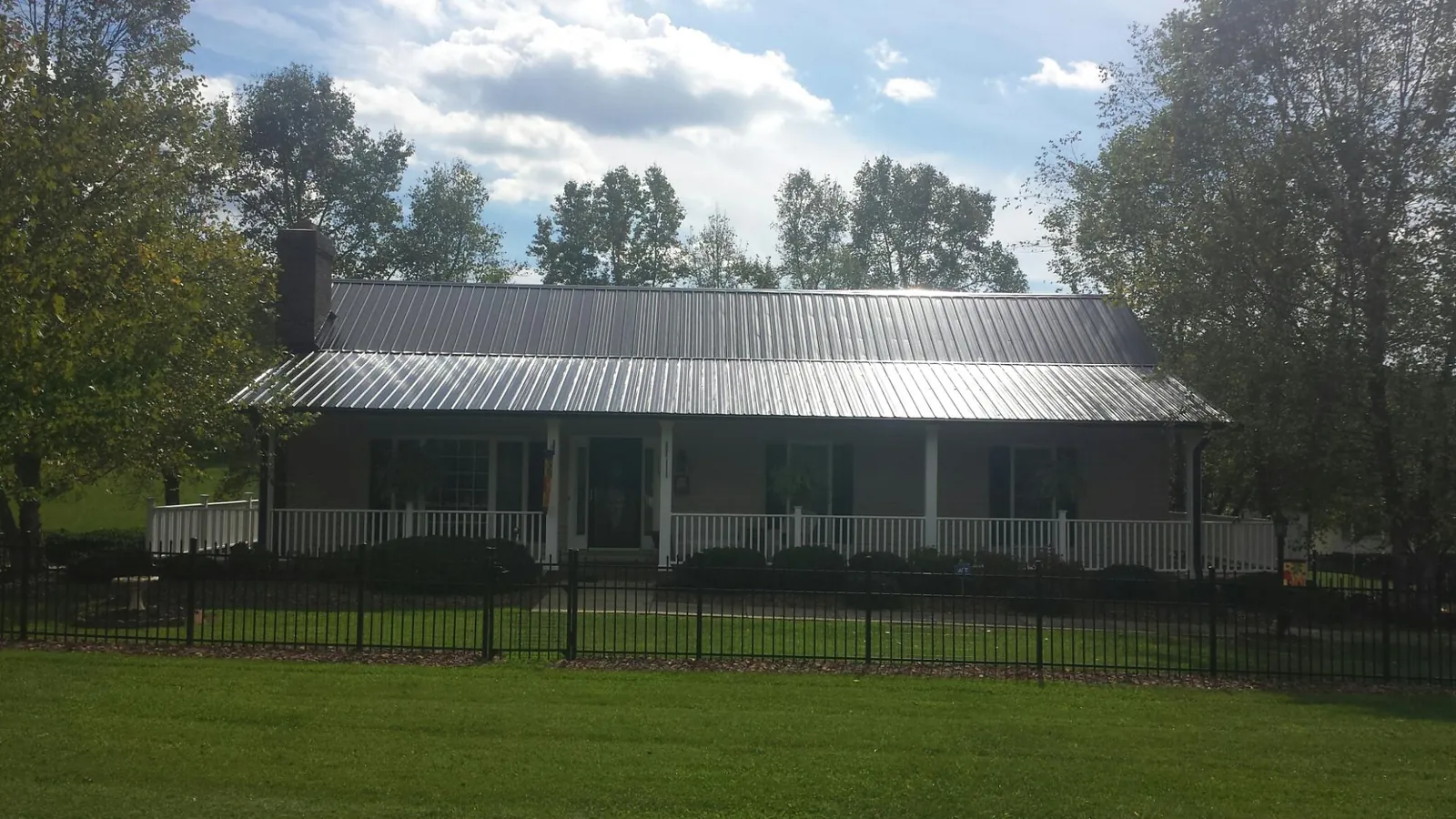 Gray metal roof on a brick ranch with a full width front porch — Gutter Guard Installation work by our crew in Priest River
