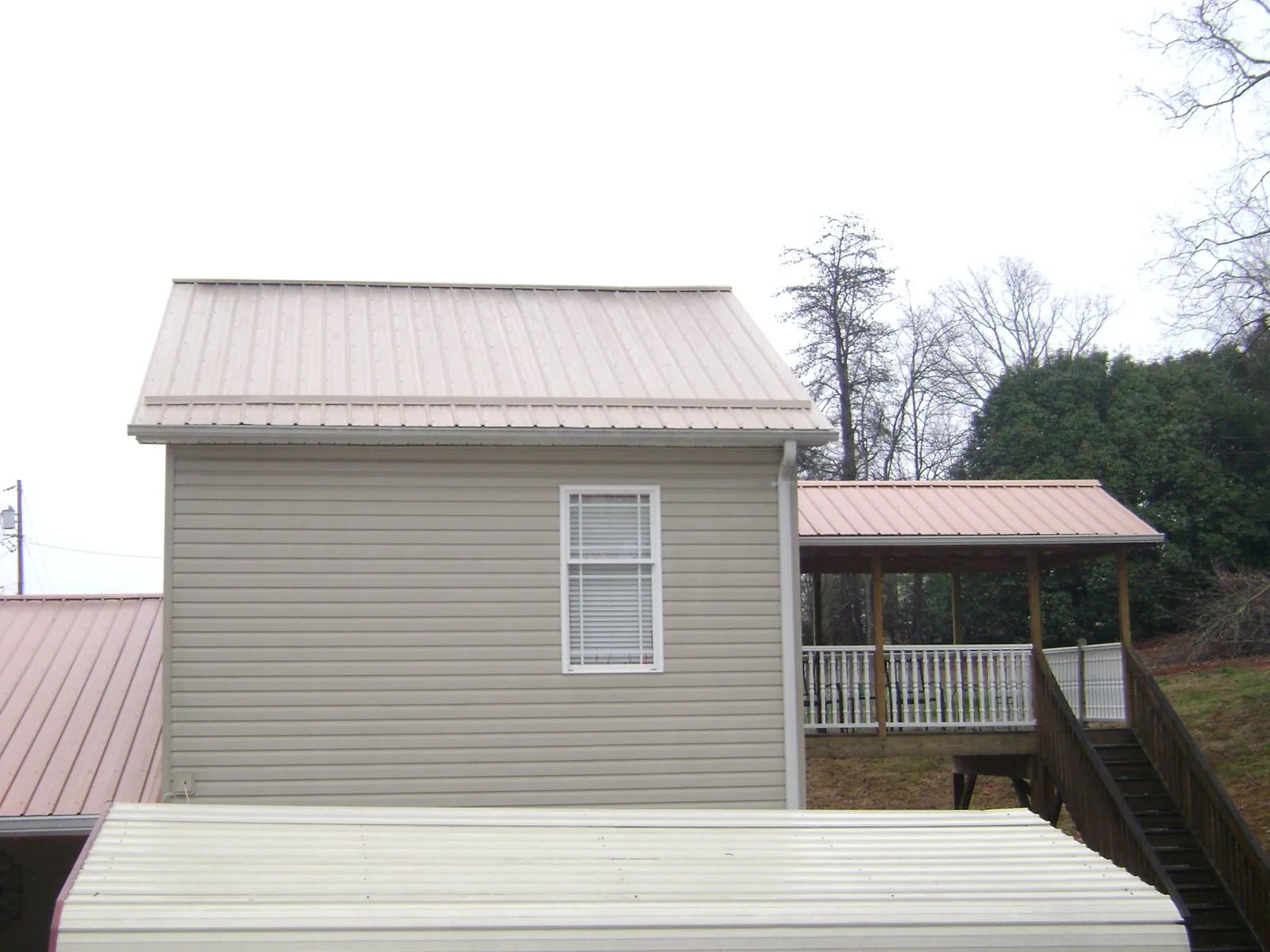 Tan metal roofs on a two story addition and attached porch, from a Roof Replacement job in Priest River