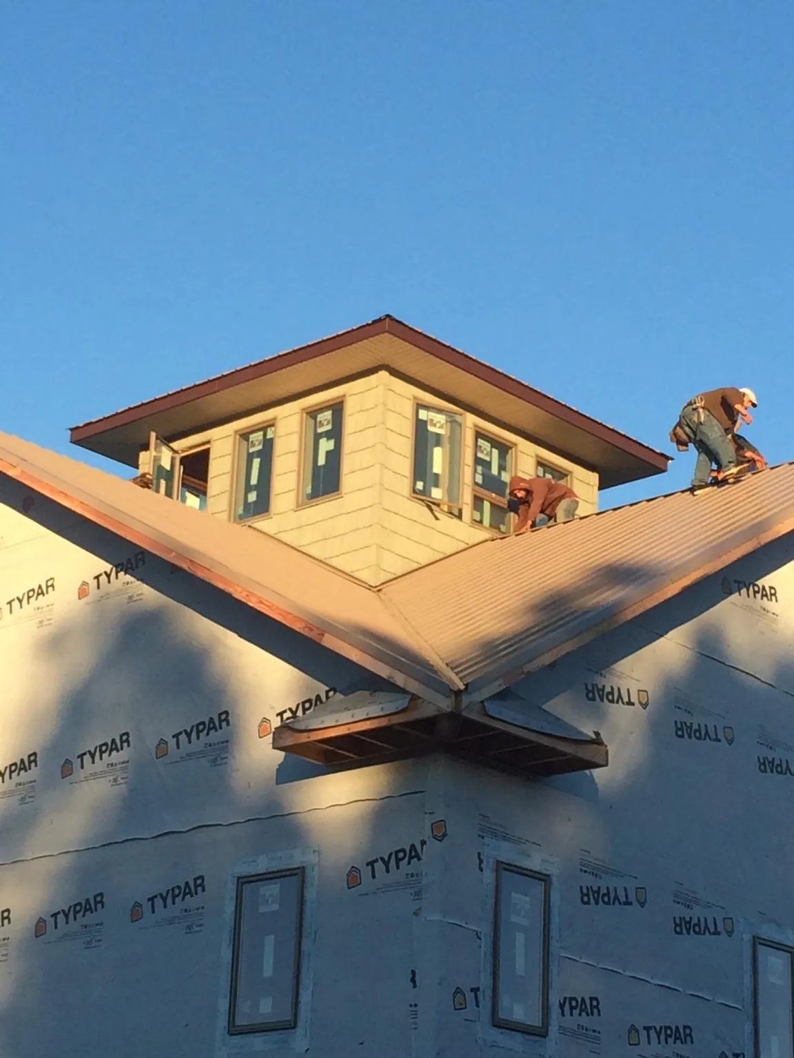 Roofers working around a rooftop cupola on a new metal roof at sunset — Roof Waterproofing in Priest River by Roofing Brothers